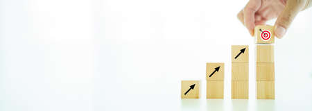 Creativity in business growth concept on wooden blocks with copyspace. Man putting the bullseye target and arrow icon on the top of chart.の写真素材