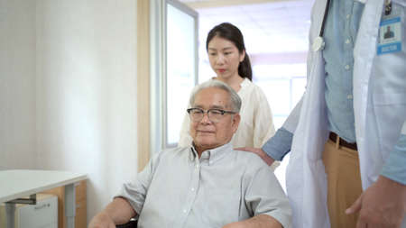 Granddaughter take her grandfather on wheelchair see the doctor or therapist at hospital. Health care and wellbeing in Asian family - aging society concept.の写真素材