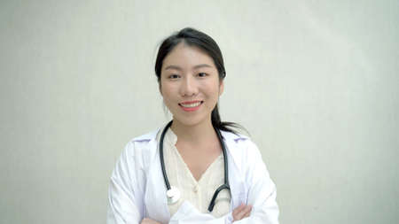 Portrait of Asian female doctor smiling and arms crossing to camera, attractive - good looking woman doctor in hospital looking at camera close up.の写真素材