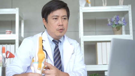 Professional specialized doctor talking with patient via medical online video conference on laptop computer, tele medical service concept. orthopedic doctor giving a medical consulting.の写真素材