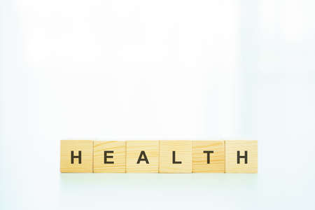 Words Health on the wooden block close up, man turning the words between health and wealth. The conceptual of healthcare - wellbeing and security in financial.の写真素材