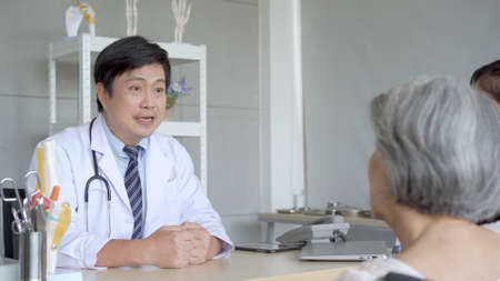 Asian young woman taking her mother to see an orthopedic doctor at hospital. Elder woman talking and having a consulting with orthopedic doctor about disease. Wellness and health care concept.の写真素材