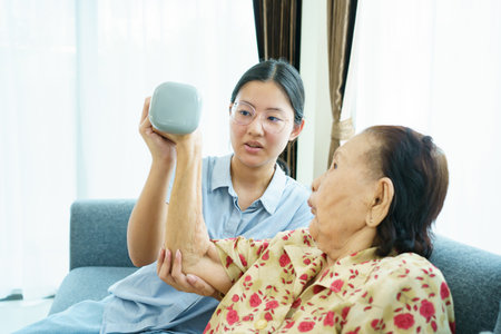 Asian elder woman doing a physical therapy exercise with her granddaughter by using dumbbells, wellness - wellbeing and health care in elder people in aging society concept.の写真素材