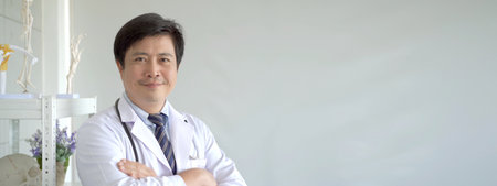 Happy Asian male doctor making arms crossed and smiling to camera.の写真素材