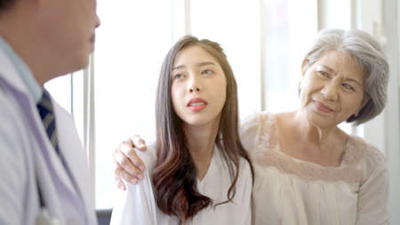 Asian young woman and her mother talking to doctor for the health advise.の写真素材