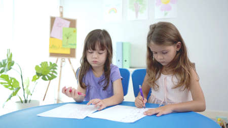 Happy kindergarten children rising their hand when teacher asking a question. Happy kindergarten little girl rises her hand up to answer a math questions.の写真素材