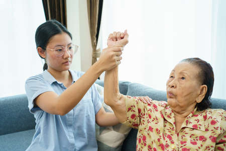 Asian elder woman doing a physical therapy exercise with her granddaughter, wellness - wellbeing and health care in elder people in aging society concept.の写真素材