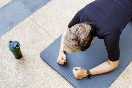 Active Asian young man making an outdoor body weight exercise close up, sportsman doing body weight workout by pushup and plank. Asian sportsman exercising for muscle and body building.の写真素材