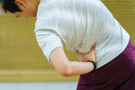 Asian young man having a health problem from working in the office, man got an office syndrome or backache. Man get hurt at his back and trying to do a self massage.の写真素材