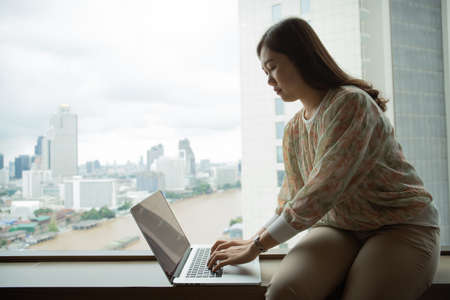 Happy Asian young woman making a video conference on laptop computer while living in the living room.の写真素材