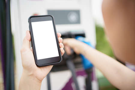 Empty screen of mockup smartphone isolated with clipping path. Asian young woman using ev charging application on smartphone connect with the charging station, BEV or electric vehicle charging stationの写真素材