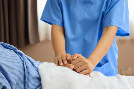 Unrecognizable nurse and patient portrait, nurse holding a coma patient's hands and give him an encouragement. Empathy and caring in senior adult - retirement people.の写真素材