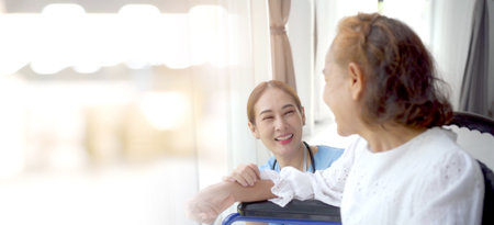 Asian elder woman talking to doctor in the reception desk in hospital about medicine and treatment. Asian doctor giving an advice and explaining to elder female patient with empathy.の写真素材