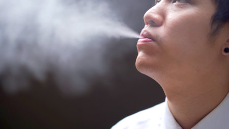 Asian white collar worker smoking an e-cigarette, alternative smoking for health.の写真素材