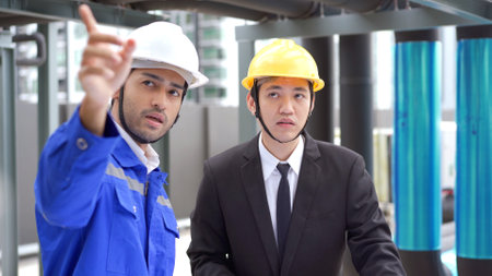 Professional Asian foreman and construction manager talking - discussing about building structure plant together. Businessman and construction engineer having a discussion.の素材 [FY310190875902]