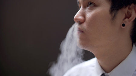 Asian white collar worker smoking an e-cigarette, alternative smoking for health.の写真素材