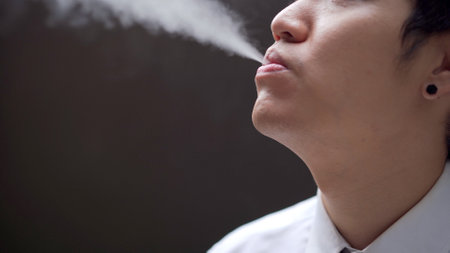 Asian white collar worker smoking an e-cigarette, alternative smoking for health.の写真素材