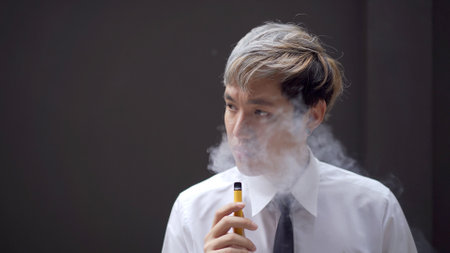 Asian white collar worker smoking an e-cigarette, alternative smoking for health.の写真素材