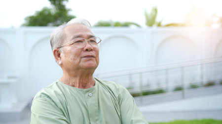 Happy - cheerful Asian elder adult age between 70-80 years old relaxing at the park. Mental health care and wellness in elderly people concept. Happy old man standing at the park and smiling.の写真素材