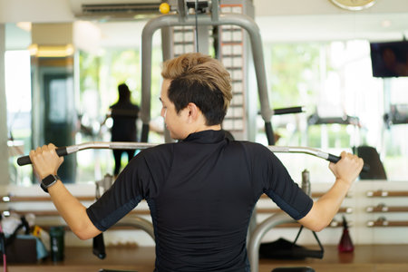 Active young Asian sportsman practice weight training in the gym by using weight pulldown machine. Man doing a weight training exercise for muscle and body building. Healthy people - work life balanceの写真素材