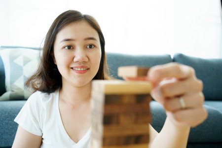 Happy Asian woman enjoy playing a wood block game in the living room during the free time.の写真素材