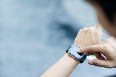 Active Asian young sportsman using a smartwatch or smart fitness band to track his outdoor workout and activities, man reviewing an exercise and health information after finished outdoor workout.の写真素材