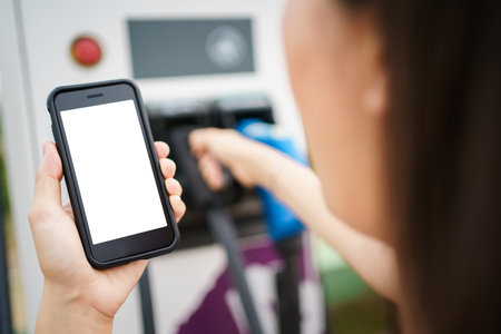 Empty screen of mockup smartphone isolated with clipping path. Asian young woman using ev charging application on smartphone connect with the charging station, BEV or electric vehicle charging stationの写真素材