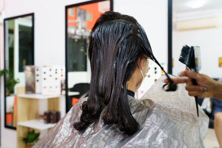 Professional hair stylist making a hair coloring and treatment in beauty and salon shop. Woman changing a hair color in professional salon shop.の写真素材