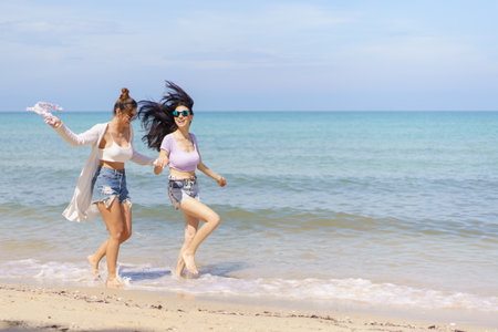 Happy female couple or bisexual couple enjoy walking along the beach together, women holding a hands together and running along the beach. LGBTQ people concept.の写真素材