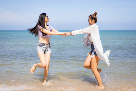Happy female couple or bisexual couple enjoy walking along the beach together, women holding a hands together and running along the beach. LGBTQ people concept.の写真素材