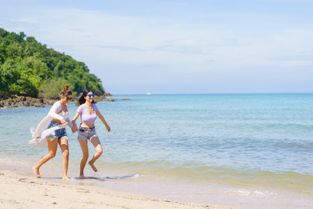 Happy female couple or bisexual couple enjoy walking along the beach together, women holding a hands together and running along the beach. LGBTQ people concept.の写真素材