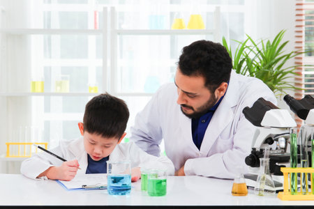 Lovely Asian young boy in lab coat enjoy doing an experiment and studying a science. Smart Asian little boy learning a science experimental with expertise scientist or science researcher in laboratoryの写真素材