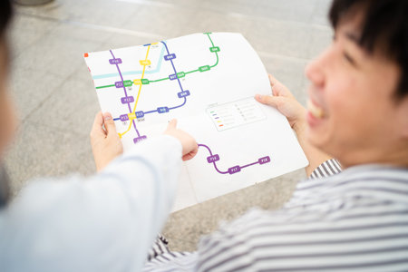 Happy cheerful Asian family traveling in the downtown together concept. Father looking at the railway station map with his son and pointing a forefinger on the map. Asian family tourist in city.の写真素材