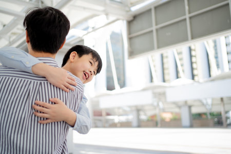 Happy cheerful Asian little boy running to his father at the railway or sky train station after his father returned from the traveling trip. Happy Asian family father and son concept.の写真素材