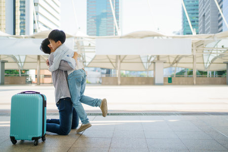 Happy cheerful Asian little boy running to his father at the railway or sky train station after his father returned from the traveling trip. Happy Asian family father and son concept.の写真素材