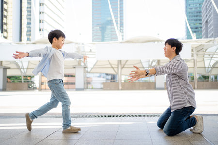 Happy cheerful Asian little boy running to his father at the railway or sky train station after his father returned from the traveling trip. Happy Asian family father and son concept.の写真素材