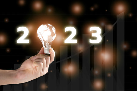 Unrecognizable businessman holding a lightbulb on hand with a beautiful illuminated letter 2023, the globalization in 2023 year concept.の写真素材