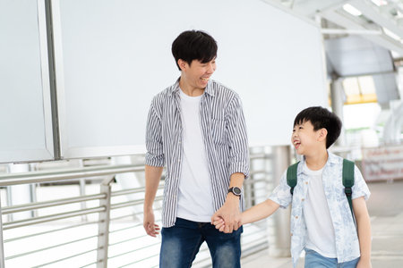 Father taking his son going to school, a man holding child hand while walking to school together.の写真素材