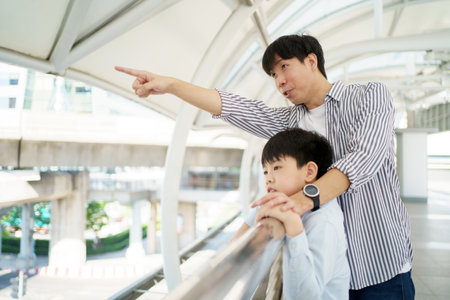 Happy cheerful father and son traveling in the city or downtown together. Asian man taking his son to travel at the downtown district and walking together. Family time and traveling concept.の写真素材