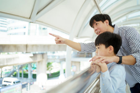 Happy cheerful father and son traveling in the city or downtown together. Asian man taking his son to travel at the downtown district and walking together. Family time and traveling concept.の写真素材