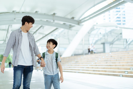 Father taking his son going to school, a man holding child hand while walking to school together.の写真素材