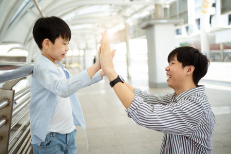 Boy and his father touching hands together.の写真素材