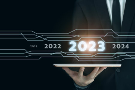 Unrecognizable businessman holding a digital tablet and showing a business chart or bar graph with a year 2023 in hologram with copy space. A successful and growth in business in 2023 concept.の写真素材
