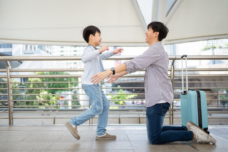 Happy cheerful Asian little boy running to his father at the railway or sky train station after his father returned from the traveling trip. Happy Asian family father and son concept.の写真素材
