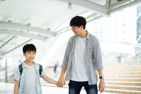 Father taking his son going to school, a man holding child hand while walking to school together.の写真素材
