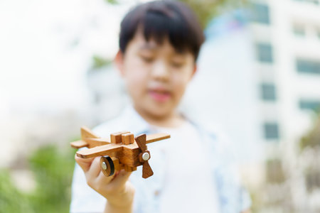 Asian little boy playing with a wooden airplane toy that dreamed to be a pilot in the future. A concept of dreaming to be a pilot of little kids.の写真素材