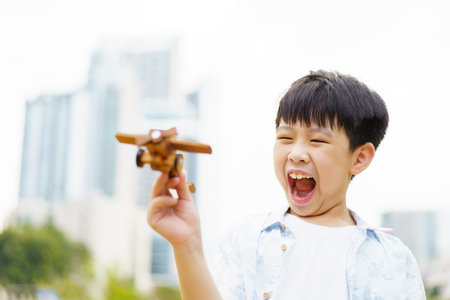 Asian little boy playing with a wooden airplane toy that dreamed to be a pilot in the future. A concept of dreaming to be a pilot of little kids.の写真素材