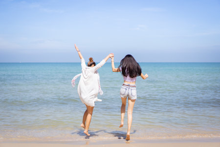 Happy female couple or bisexual couple enjoy walking along the beach together, women holding a hands together and running along the beach. LGBTQ people concept.の写真素材