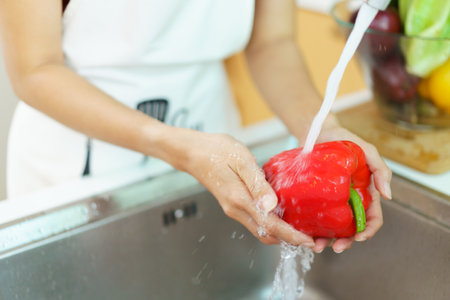 Happy healthy Asian woman washing a vegetables in domestic kitchen faucet before cooking. A housewife preparing and cleaning a fruits and vegetables carefully for cooking a healthy meal.の写真素材