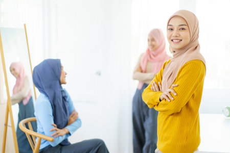 Happy Asian muslim businesswomen having a discussion together in office, modern muslim society and working environment concept. Asian Muslim women friends talking together.の写真素材